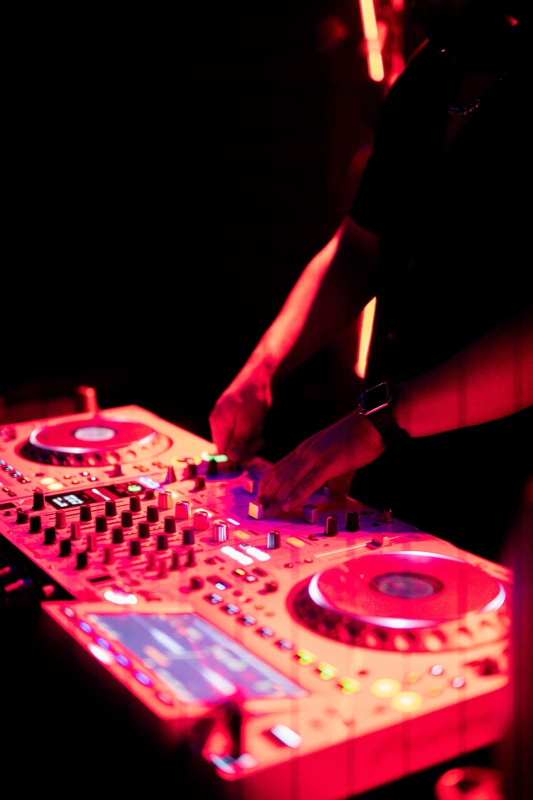 A DJ working the decks under red stage light